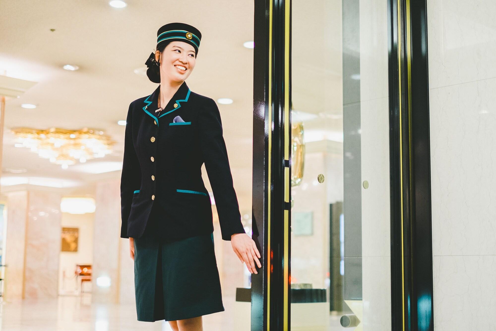 فندق نيو أوتاني هاكاتا فوكوكا المظهر الخارجي الصورة A female doorman at the entrance of a hotel